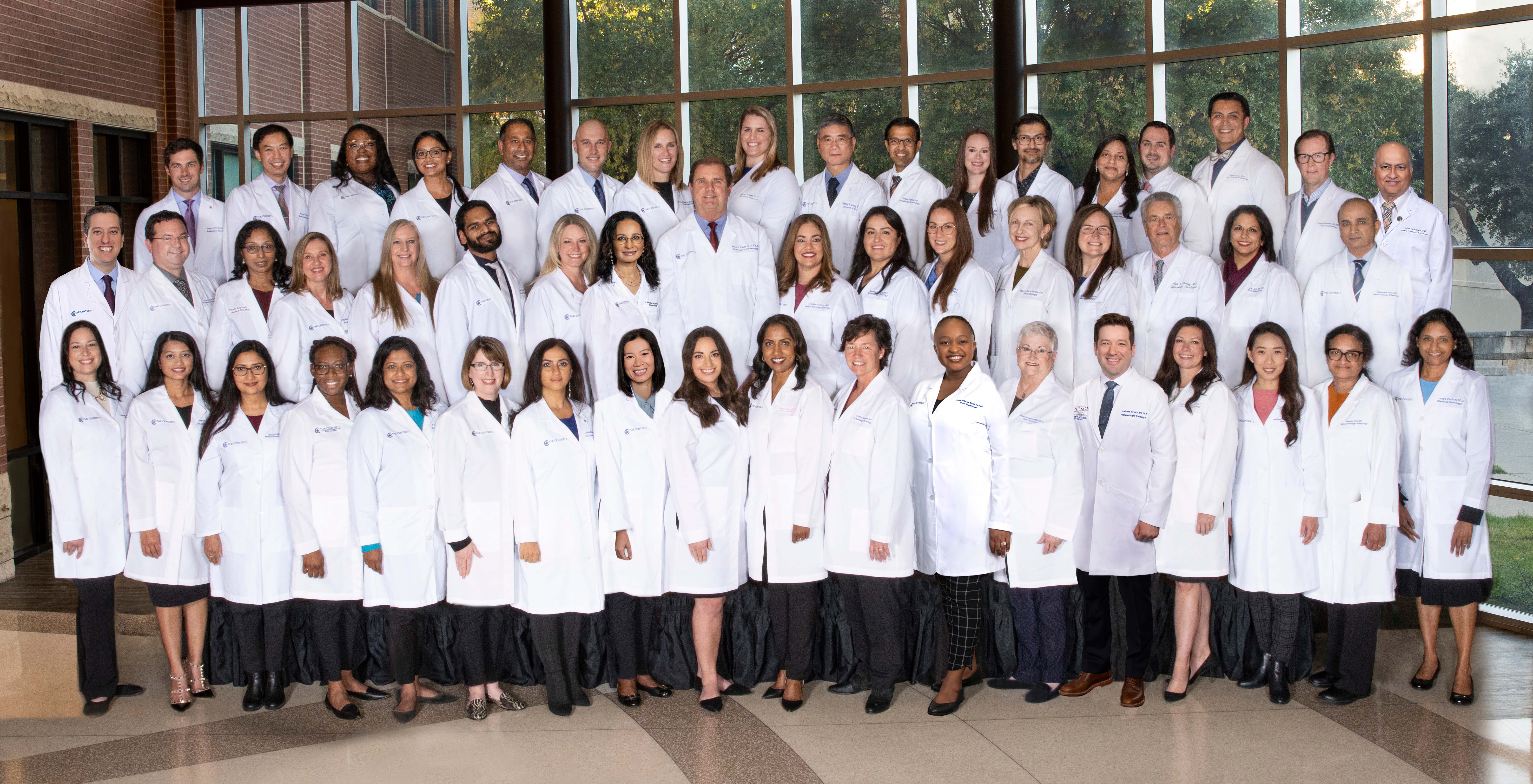 Group of medical professionals in white lab coats posed indoors.