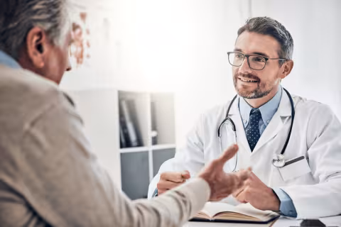 Patient talking with a doctor in an office, both seated at a desk.