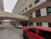 Red truck and white SUV parked outside a hospital building with a skybridge overhead.