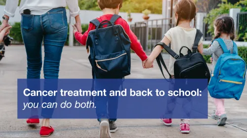 Three young children with backpacks holding hands, walking with an adult.